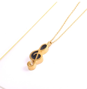 Macro view of gold-toned musical note pendant with black enamel inlay on white background