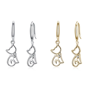 Macro detail of cat-shaped silver and gold earrings with cubic zirconia stones
