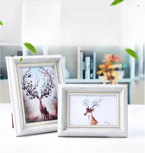 Detail of white vintage picture frames with gold inner edges and artistic deer prints