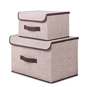 Detalle de cajas de almacenaje de tela beige apilables con asas marrones y tapa