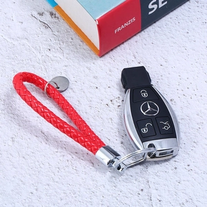 Macro detail of red hand-woven leather keychain with silver metal clasp and car key