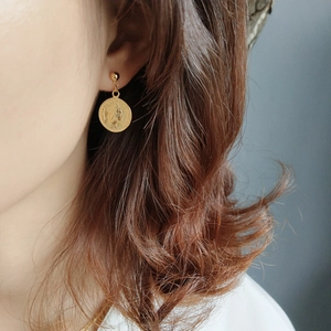 Close-up of a gold coin earring featuring Queen Elizabeth profile on a female model
