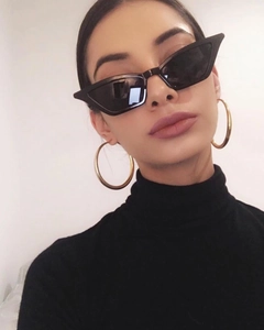 Close-up of black cat eye sunglasses and gold hoop earrings on a fashion model