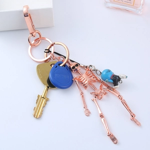 Rose gold skeleton keychain with blue cartoon figure and gold key accessory