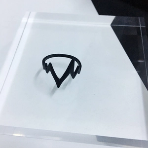 Minimalist black stainless steel lightning heart rate ring on a clear display stand