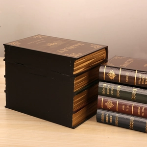 Stack of vintage book-shaped storage boxes in wood with gold accents and classic titles