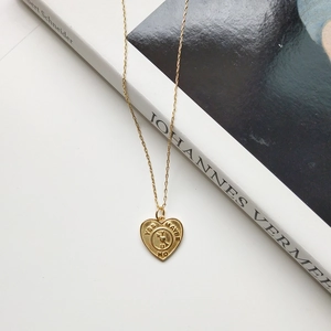Detail of gold heart pendant with rotating arrow pointer on a book background