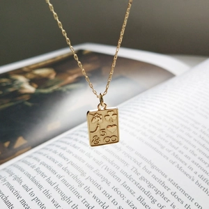 Macro shot of gold rectangle pendant with heart and infinity symbols on a book