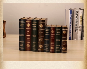 Macro shot of vintage style decorative faux book boxes with golden spine titles on wood