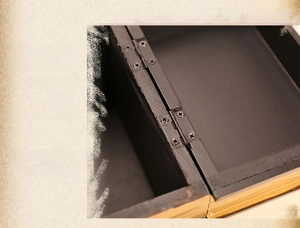 Detail of sturdy black metal hinge and golden trim on a vintage faux book storage box