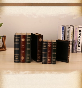 Detail of vintage faux book storage boxes with classic gold-foiled book spines on a desk