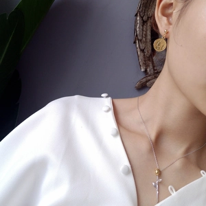 Detail of Little Prince rose pendant necklace and vintage coin earrings worn on model