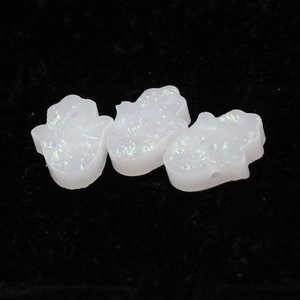 Detailed macro shot of white hamsa hand resin beads with iridescent opal glitter finish