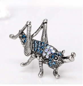 Detailed view of vintage silver grasshopper brooch with blue rhinestones and crystals