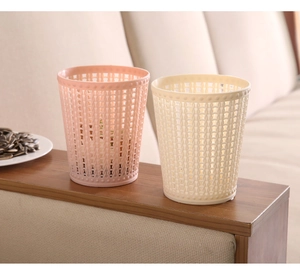 Pink and beige hollow woven texture plastic mini desktop trash cans on wooden table