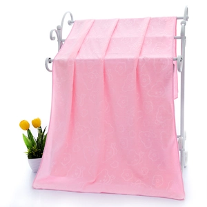 Pink absorbent microfiber towel with embossed bear pattern hanging on a white rack