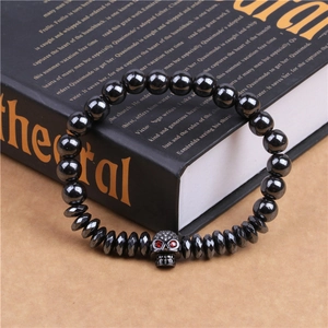 Détail de perles d'hématite noire et crâne en cuivre avec yeux en zircon rouge éclatant