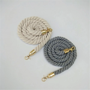 Detail view of woven beige and grey bag straps with gold metal swivel spring hooks
