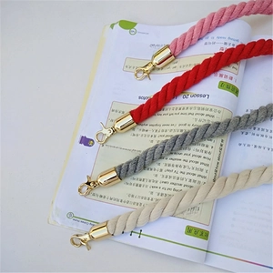 Detail of woven cotton shoulder straps in four colors with gold metal clasps on a book