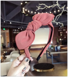 Detailed close-up of a dusty pink fabric headband with a large pleated bow design