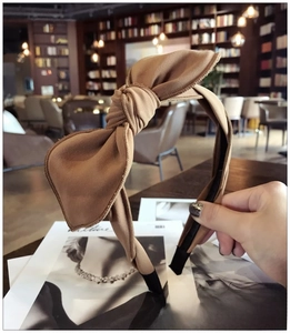 Detailed view of a caramel fabric headband featuring a large bow and non-slip black tips