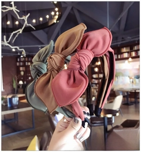 Detailed view of three fabric bow headbands in pink, brown and green colors