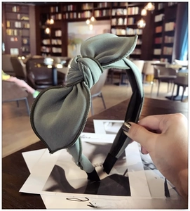 Detailed texture of a sage green knotted headband with ribbed fabric on a thin band