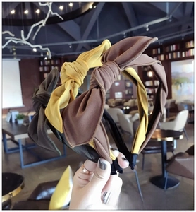 Detailed view of three fabric bow headbands in brown, mustard yellow, and olive green colors