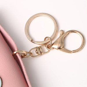 Pink faux leather owl coin purse with golden lobster clasp and keychain on white background
