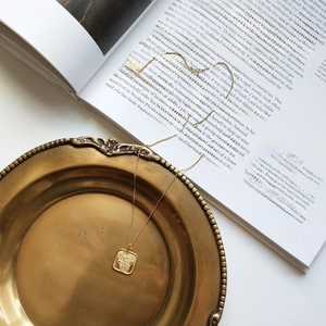 Close-up of golden square rose embossed pendant with S925 silver hallmark on art book