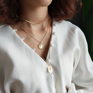 Detailed view of layered 925 sterling silver gold-plated necklaces on a model
