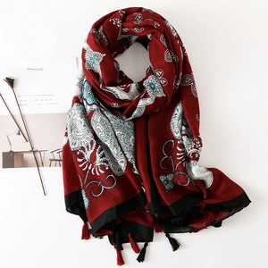 Détail d'une écharpe rouge à motif paisley avec pompons ethniques et texture lin