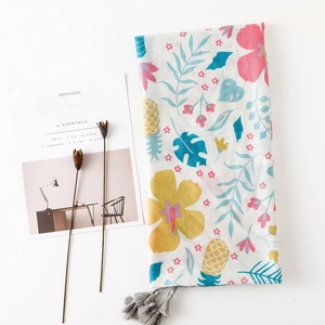 Détail de l'imprimé tropical sur écharpe en coton et lin avec pompons gris élégants