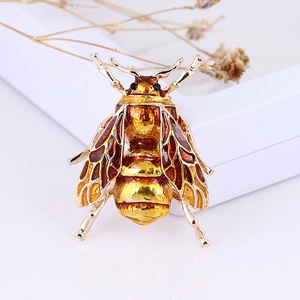 Detailed view of an amber enamel bee brooch with golden wings on a decorative background