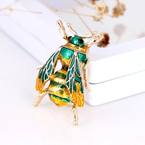 Macro shot of 3D enamel insect bee brooch with green wings and golden finish