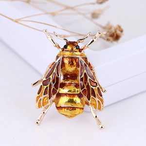 Macro view of detailed bee brooch with amber enamel wings and gold alloy frame