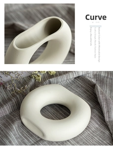 Close-up of minimalist white ceramic ring vase with matte texture and hollow design