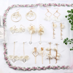 Detailed collection of elegant gold floral earrings with pearls on a soft white background