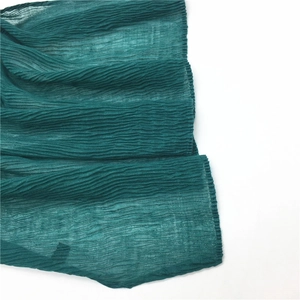Detailed macro shot of dark green crinkled cotton linen scarf showing fine pleated texture