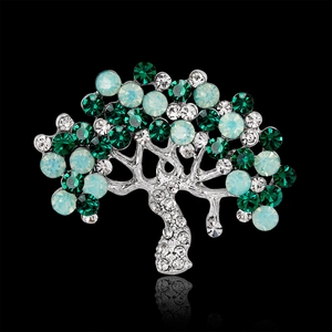 Elegant silver tree brooch with green crystals and cat eye stones on black background