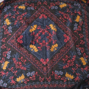 Detail of floral printed square scarf with bold red and yellow blossoms on navy blue linen