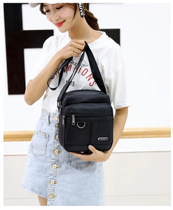 Detailed view of black nylon messenger bag with multiple zipper pockets and adjustable strap