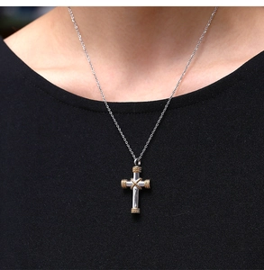 Close-up of a silver and gold stainless steel cross necklace worn by a model