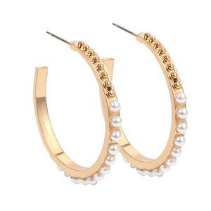 Boucles d'oreilles créoles dorées ornées de perles blanches sur fond blanc