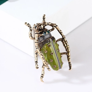 Detailed view of a gold grasshopper brooch with green enamel and sparkling crystals