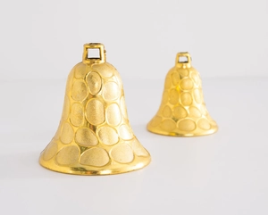 Macro detail of two golden Christmas bells with textured metal finish on white backdrop