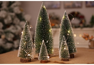 Detail of five mini snowy sisal Christmas trees with LED lights and wooden bases