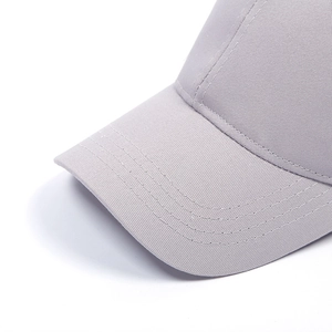 Close-up detail of reinforced stitching on the brim of a light gray baseball cap