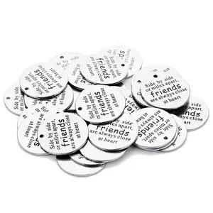 Macro shot of silver stainless steel round charms with friendship quote engraving