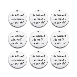 Macro shot of stainless steel round pendants with engraved motivational quote on white backdrop